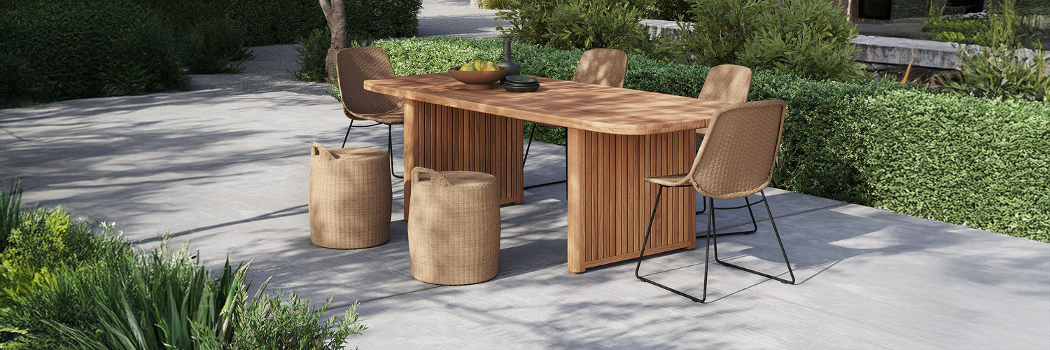 Elegant outdoor dining set from Design Warehouse featuring a solid teak dining table with fluted details, woven chairs, and wicker ottomans. A perfect blend of outdoor furniture, style, and durability for patios and gardens.