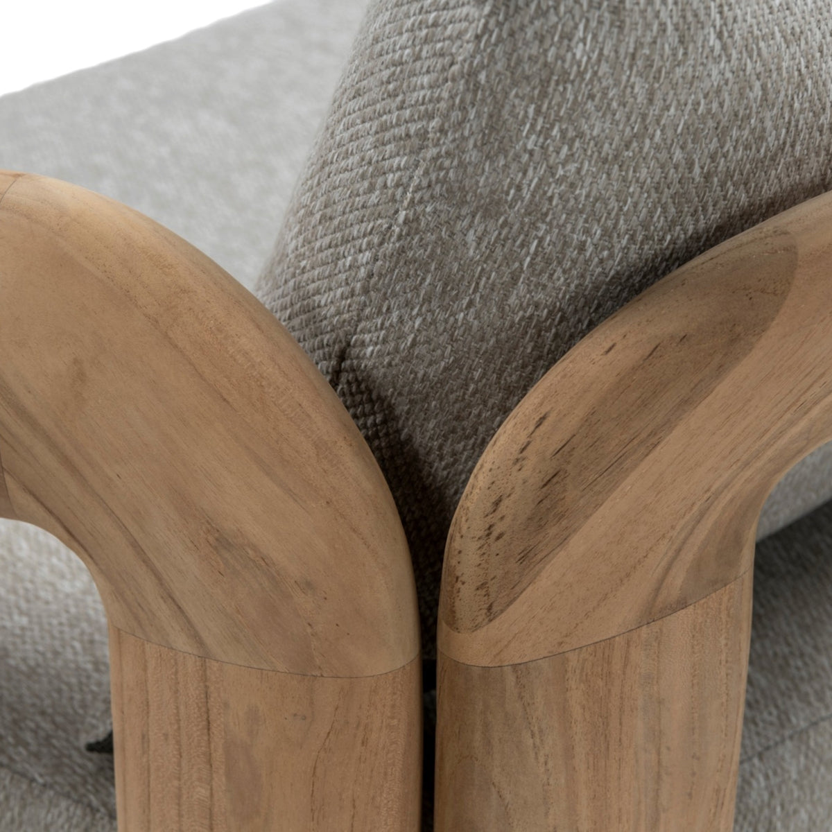Close-up of Caribbean outdoor sofa showing curved teak armrest, natural wood grain and textured grey Agora outdoor fabric