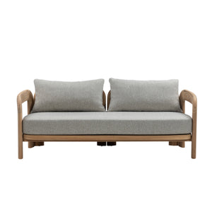 Front view of Caribbean teak outdoor sofa showing broad curved armrests, full-length grey seat cushion and two back cushions