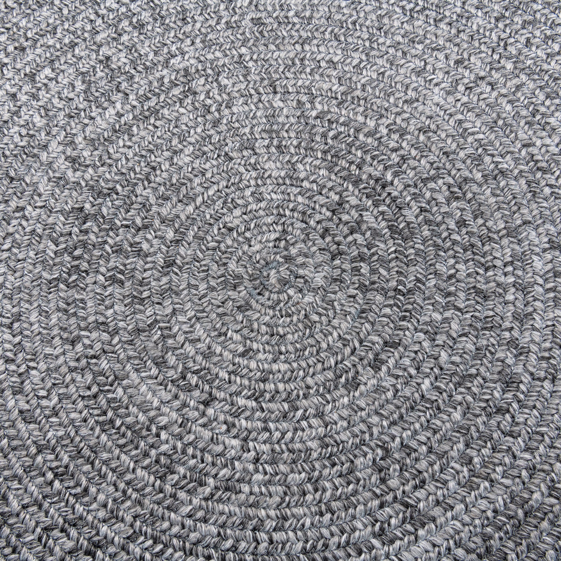 Closeup view of Cirra outdoor round handwoven floor rug in dark grey. 