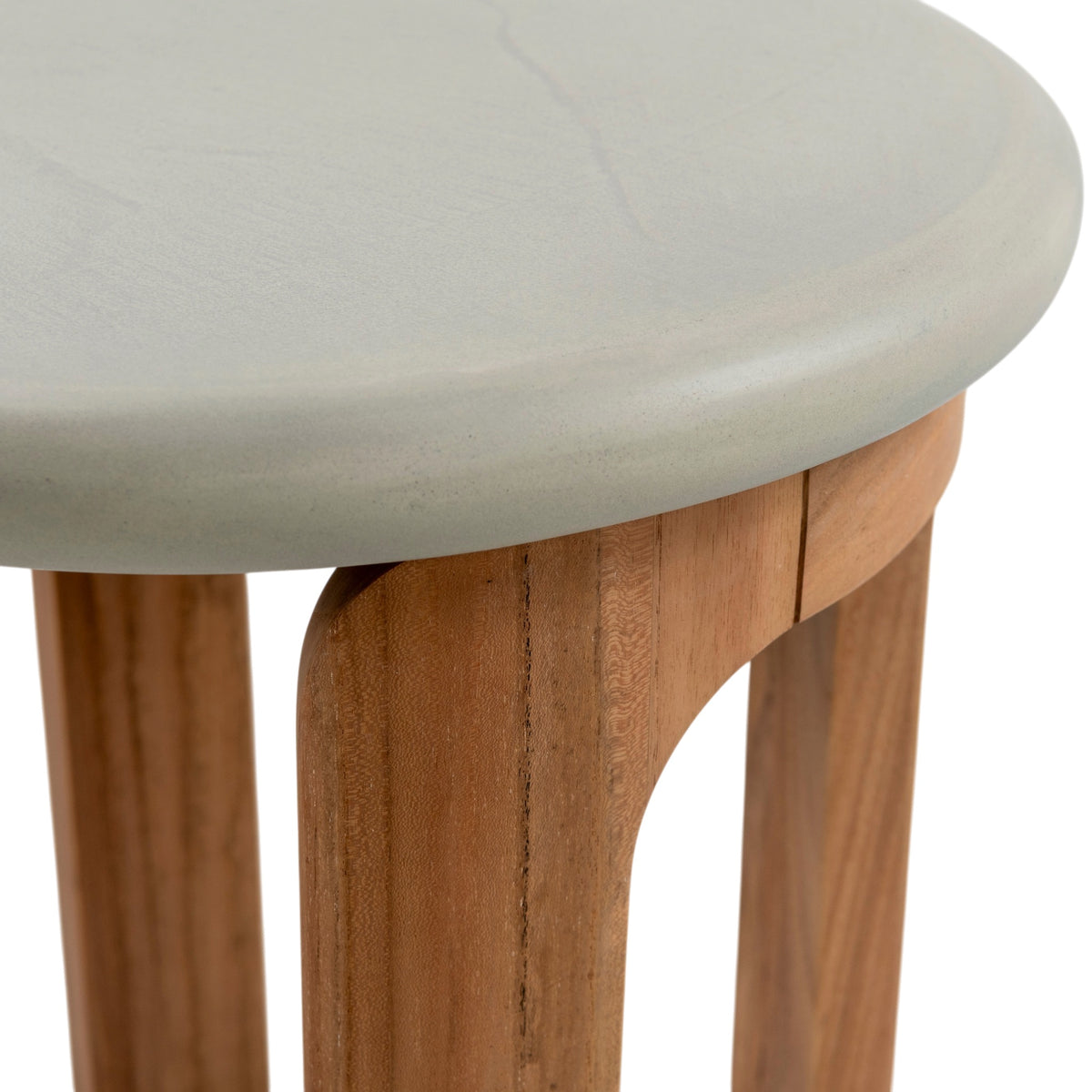Close-up of rounded concrete tabletop edge and curved natural teak support on outdoor side table