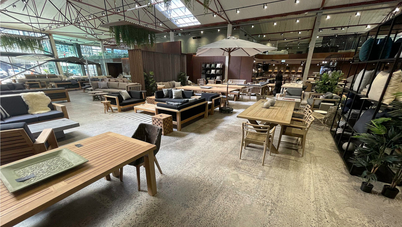 Modern outdoor furniture store with various sofas, chairs, and tables on a gray carpeted floor.