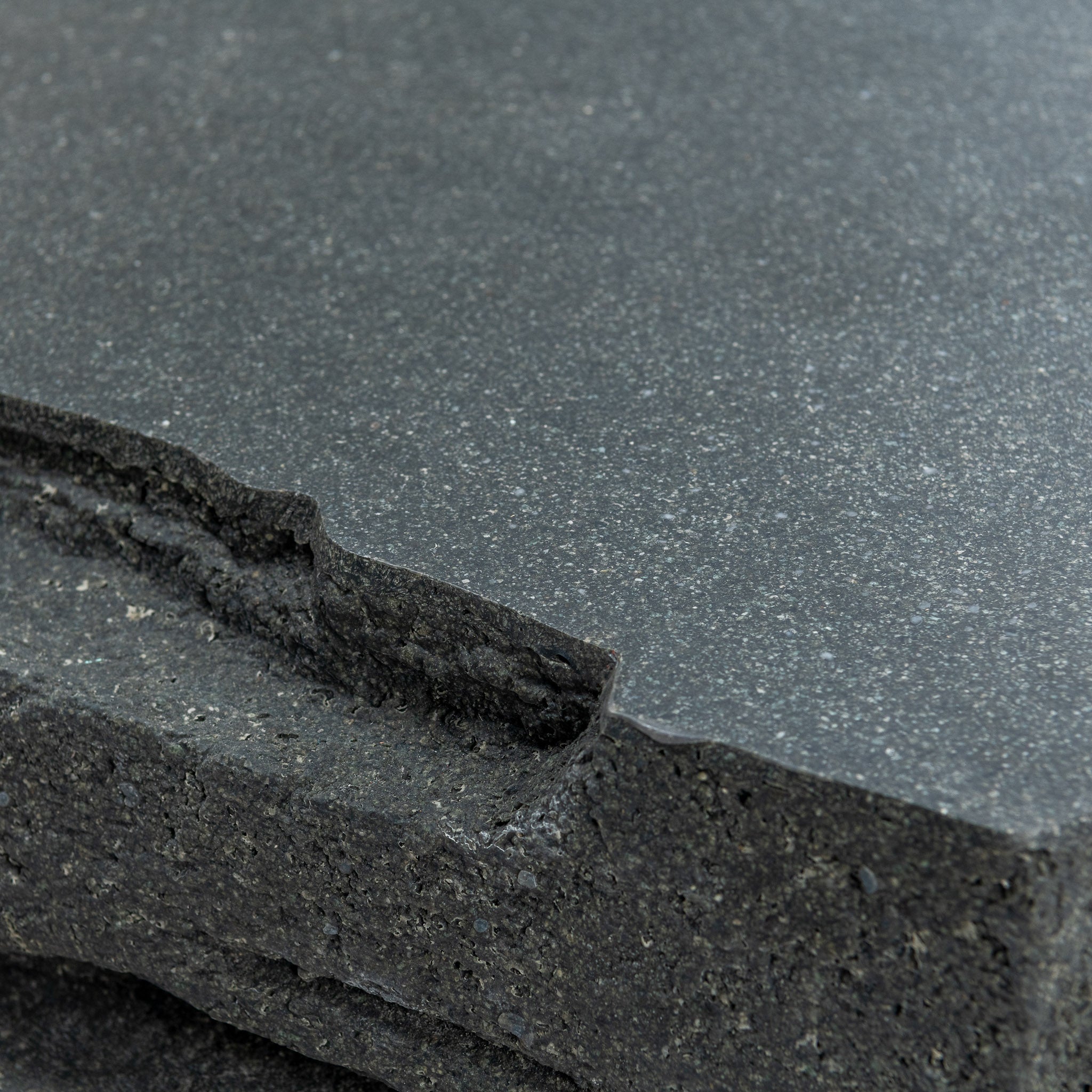 Closeup view of Fred outdoor coffee table with its jagged edges. Black finish with a trapezoid look. 