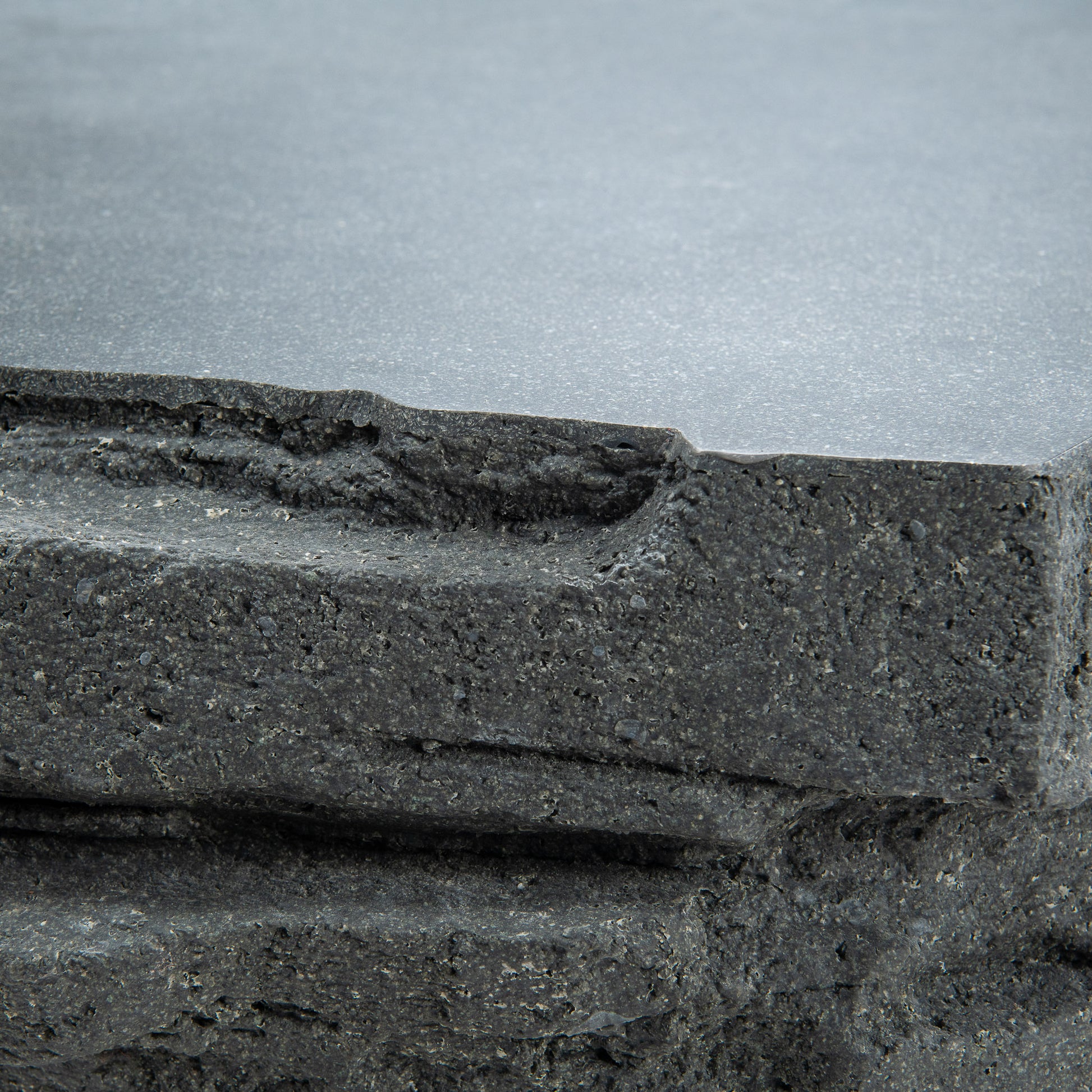 Fred outdoor coffee table closeup to show jagged edges and flat top. Made of fibrestone with unique trapezoid look.