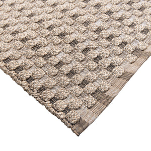 Close-up of a textured beige and brown rug with a geometric pattern on a white background.