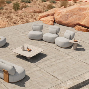 Three Menton teak lounge chairs with plush cushions on a desert patio.