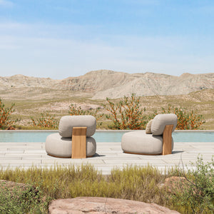 Rear view of two Menton teak lounge chairs poolside with desert as a backdrop.