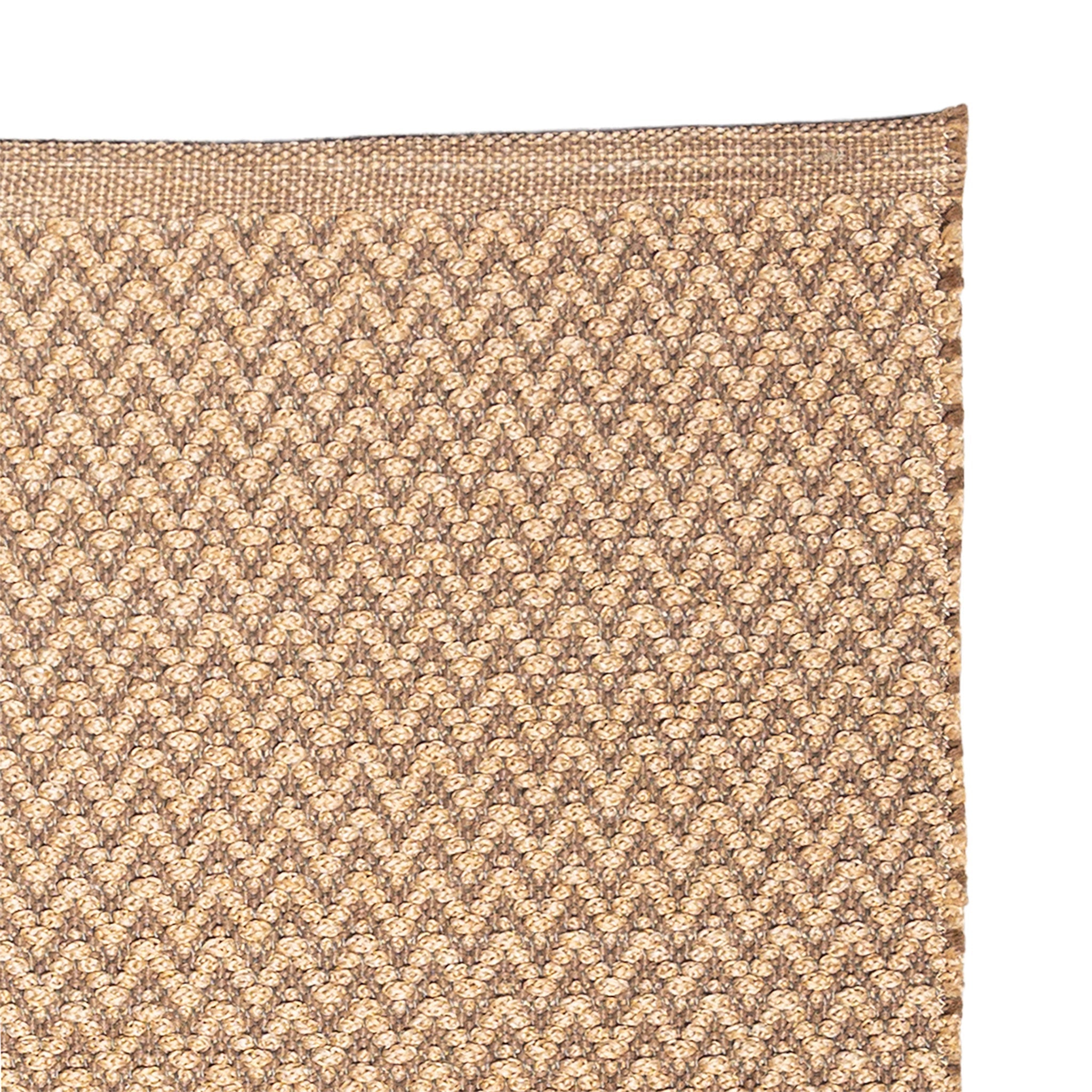 Close-up of a textured brown and beige patterned rug corner.
