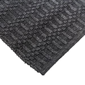 Close-up of a textured dark gray rug with a geometric pattern on a white background